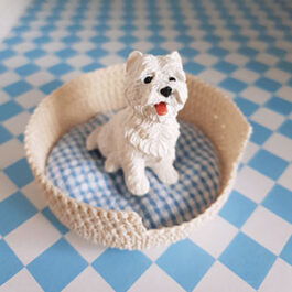 Produktbild: Vit virkad hundkorg med en söt liten prydnadshund i. Används till dockhus