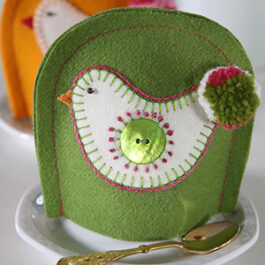 Produktbild: Grön handsydd äggvärmare med en höna som motiv på. Används till påsk