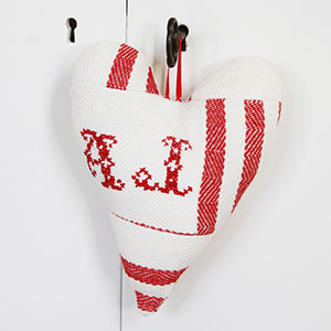Ett litet uppstoppat vitt hjärta med röda broderier i, som hänger på nyckeln till ett vitt skåp